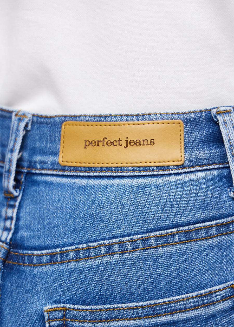 Close-up of blue denim with the Perfect Jeans leather patch at the back of the waistband.