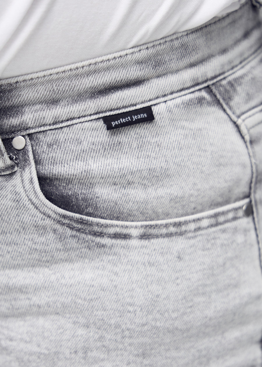 Detaljebillede af forlommen på de lysegrå denim i farven Ashes – logo og snit fremhævet på plus-size model.