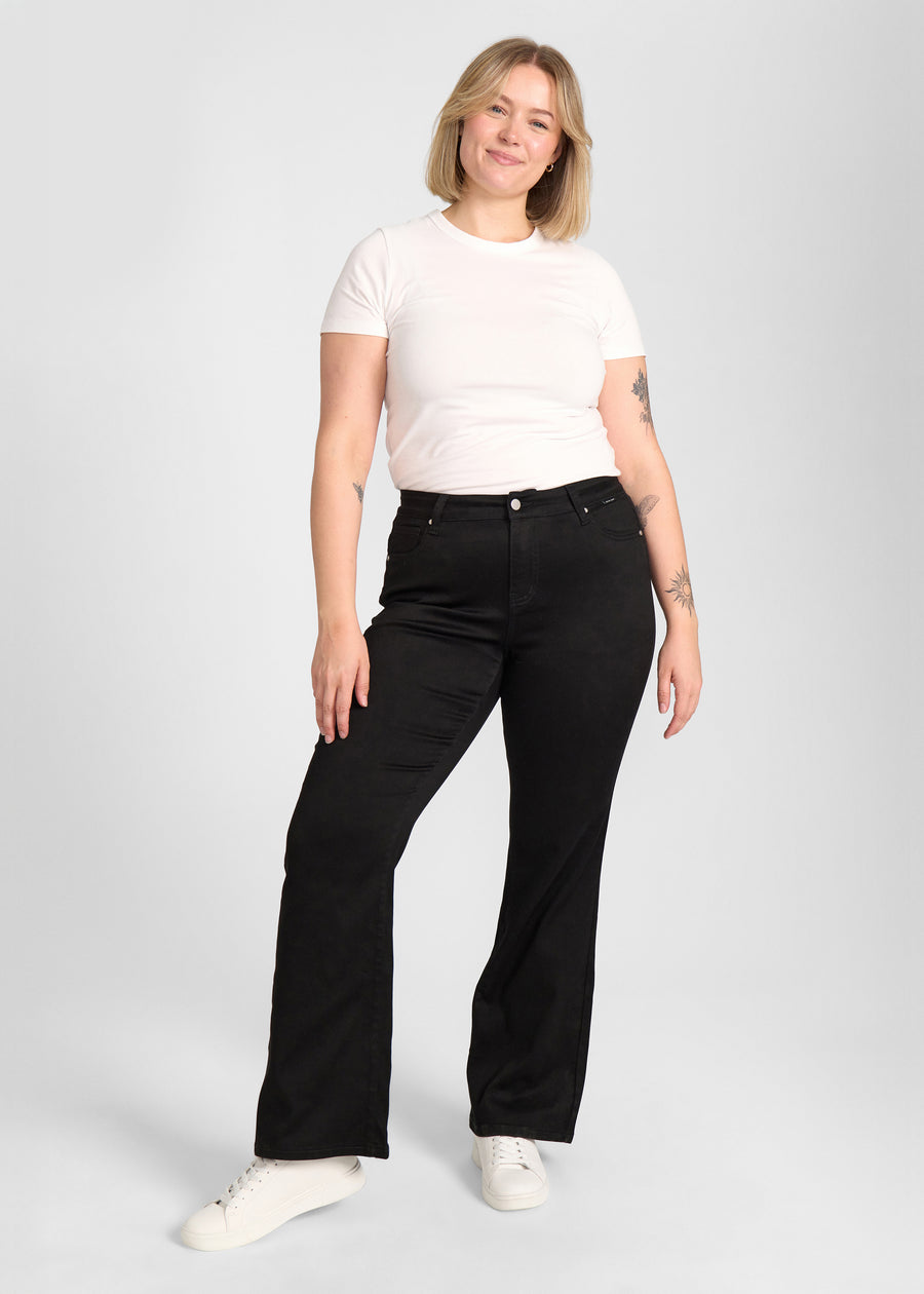 Fuldt billede af model i sort bootcut jeans på en plus-size model.