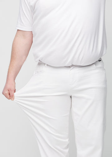 Plus-size model strækker jeansene ved låret for at vise stretch.