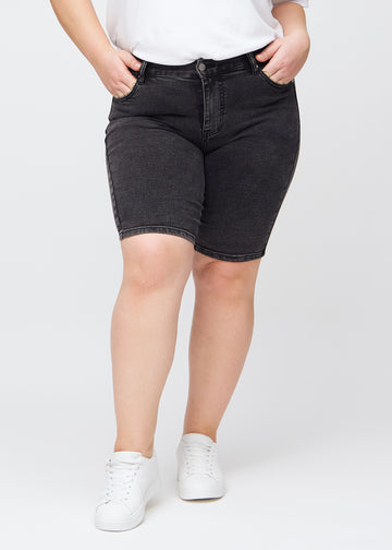 Mørkegrå denim skinny middle shorts, modelnavn Shadows, som sidder tæt til låret og slutter lige over knæet på en plus-size model, set forfra.