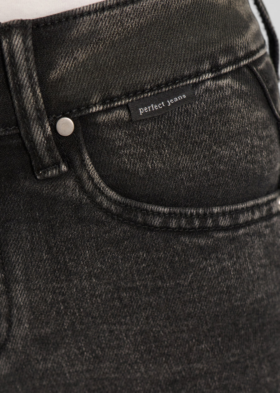 Nærbillede af mørkegrå denim med Perfect Jeans logoetiket ved forlommekanten.