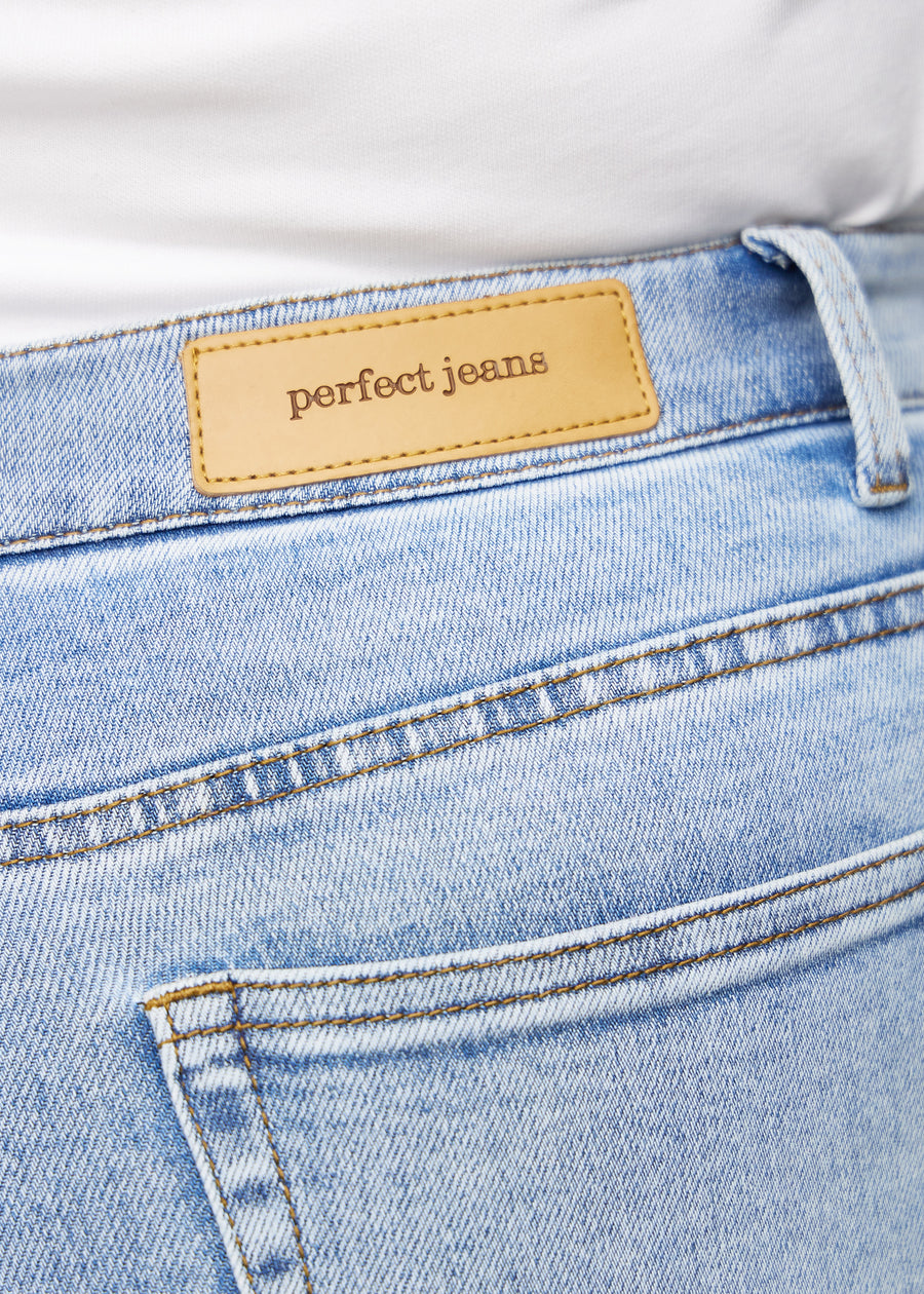 Close-up of light blue denim with Perfect Jeans leather patch at the back waistband, on a plus-size model.