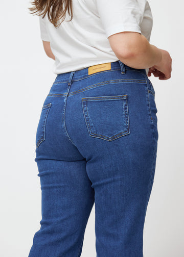 Mørkeblå mid-rise bootcut jeans i denimfarven Oceans set bagfra tæt på en plus-size model for at vise detaljer.