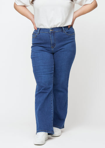 Mørkeblå mid-rise bootcut jeans i denimfarven Oceans, modelnavn Ravens, som sidder tæt fra hofte til lår og har et let svaj forneden, på en plus-size model, set forfra.