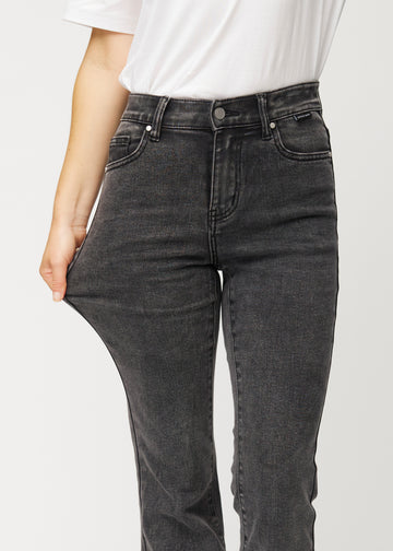 Dark grey mid-rise bootcut jeans in Shadows. A model stretches the jeans at the thigh to show the fabric&