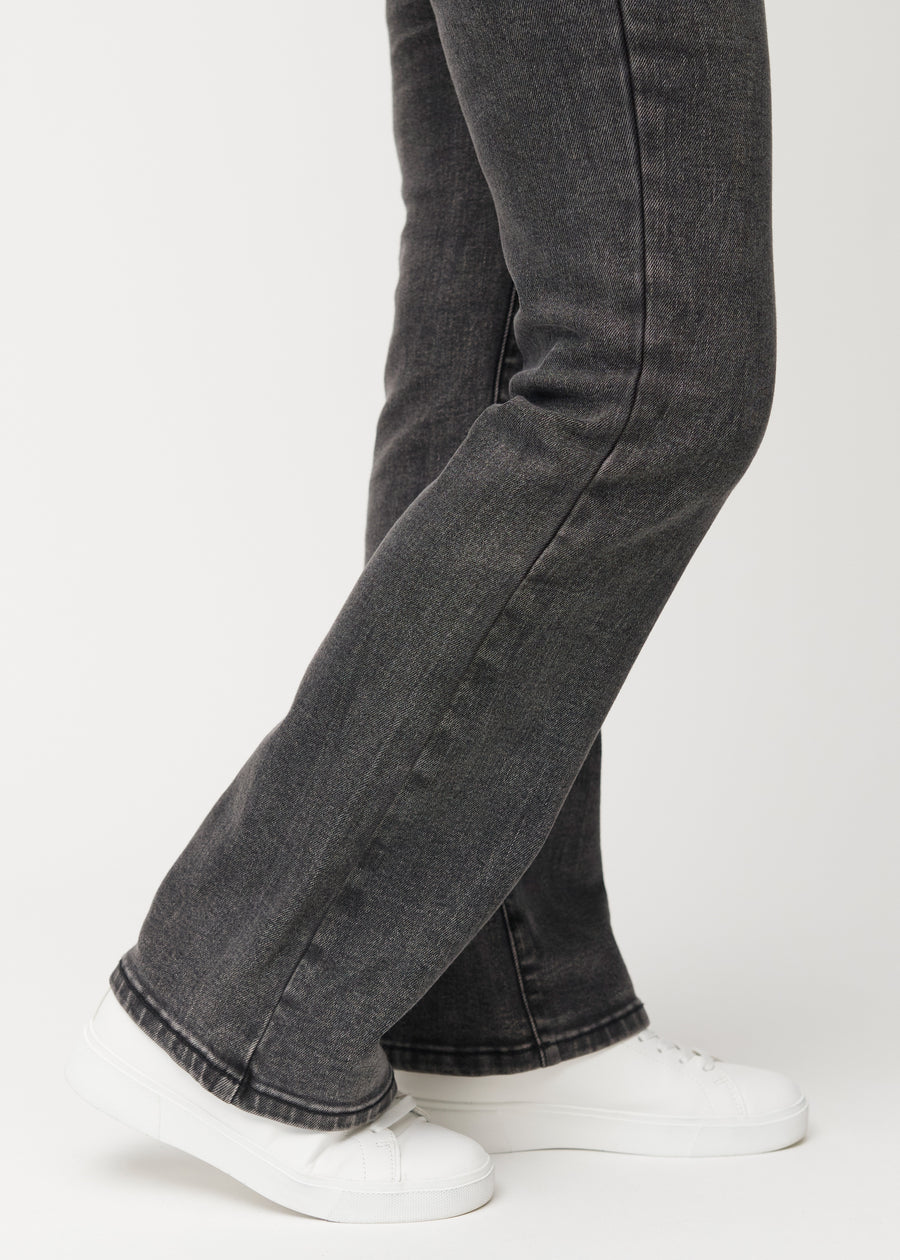 Dark grey mid-rise bootcut jeans in Shadows. Close-up of the ankle area on a model, showing the subtle bootcut flare.