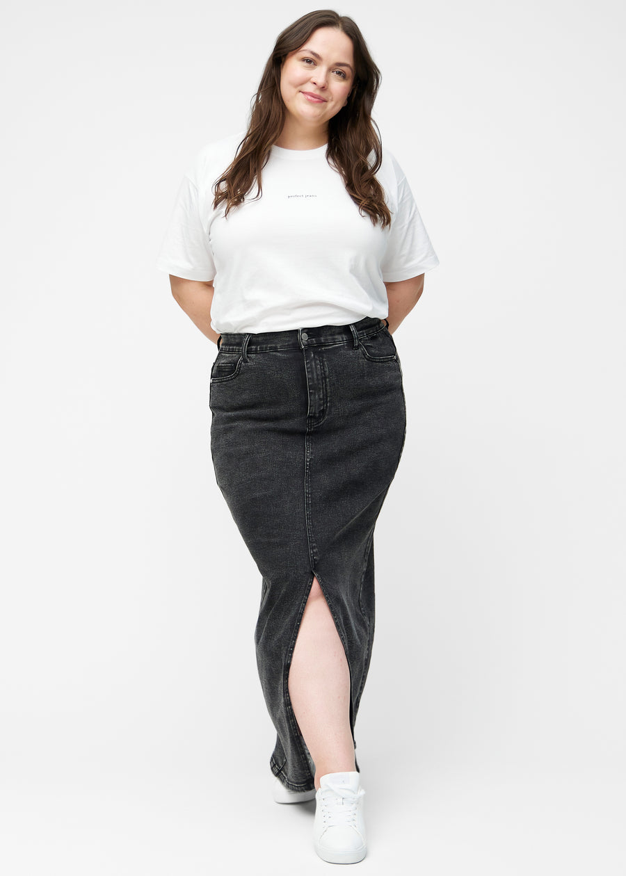 Fuldt billede af plus-size model i lang, mørkegrå denimnederdel i farven Shadows med regulær pasform og slids foran.