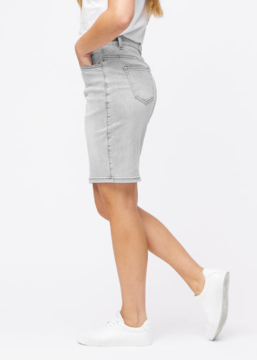 Lysegrå, tætsiddende og knælang denimnederdel set fra siden på model.