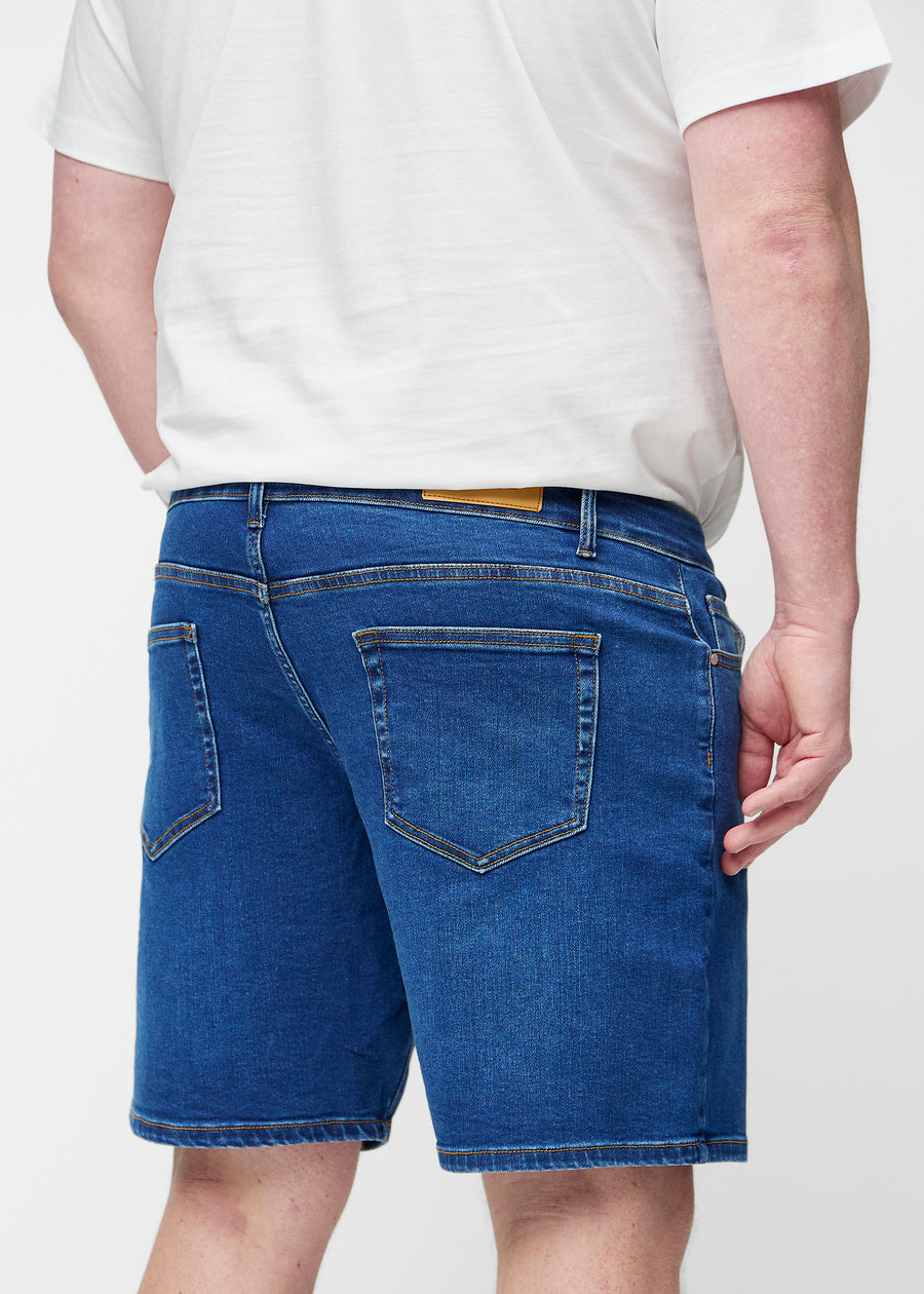 Dark blue denim shorts for men in the colour Oceans seen from the back close up on a plus-size model.