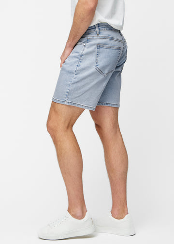 Model stretches light blue denim shorts for men in the colour Waves at the thigh to show the material’s stretch.