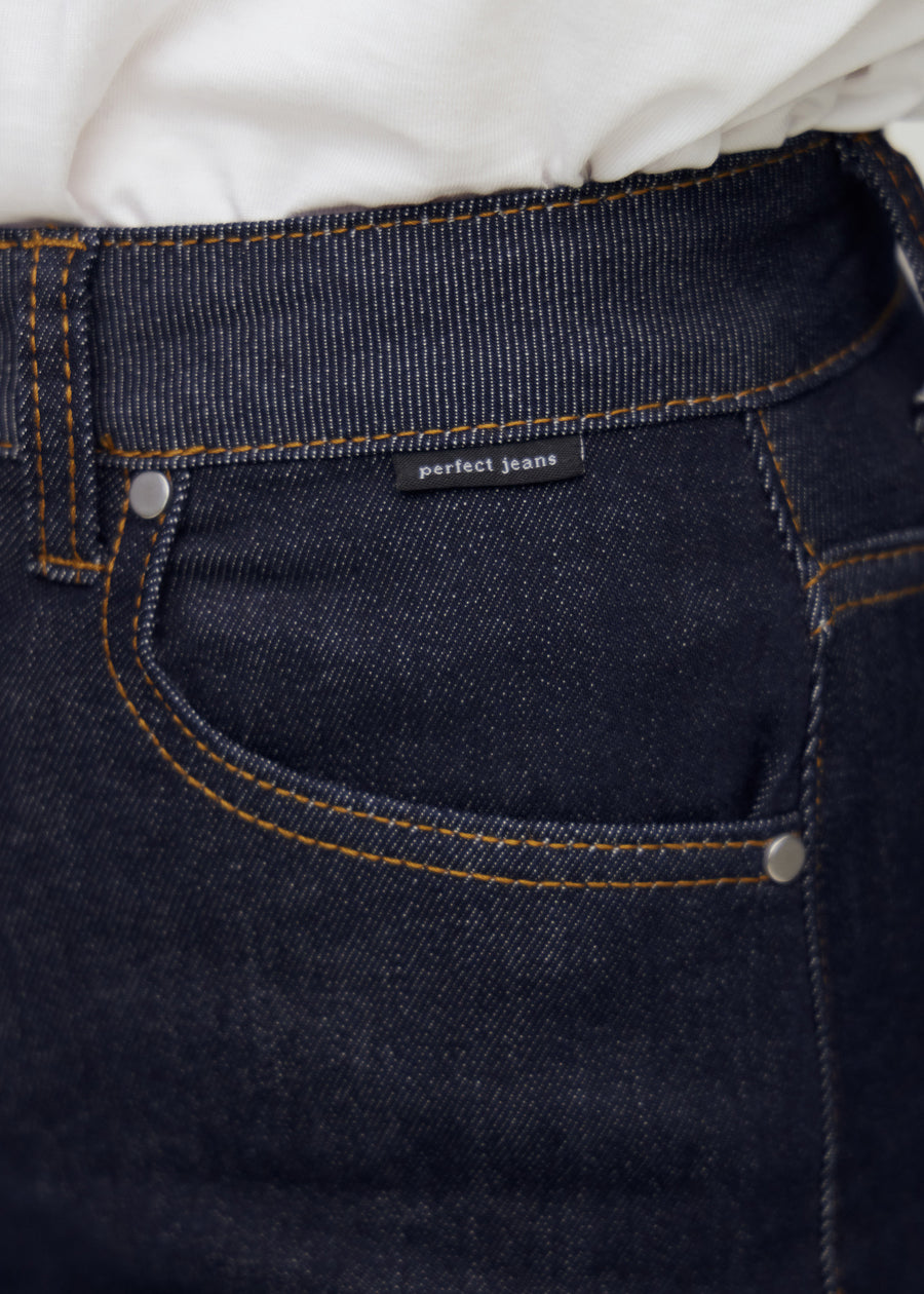 Close-up of deep dark blue denim with Perfect Jeans logo label at the front pocket edge.