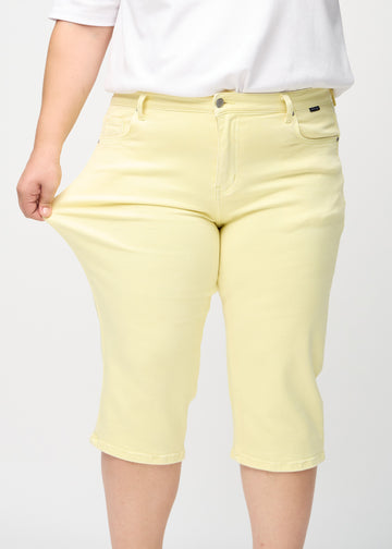 Plus-size model stretches the capris at the thigh to show the stretch.