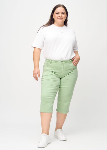 Full image of a plus-size model wearing light green regular capris.