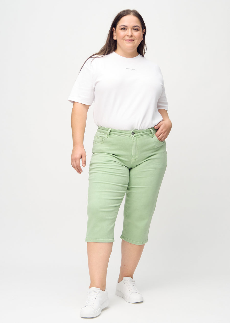 Full image of a plus-size model wearing light green regular capris.