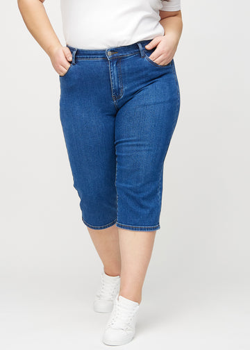 Dark denim regular capris, model name Oceans, which have a straight fit through the leg and end just below the knee on a plus-size model, seen from the front.