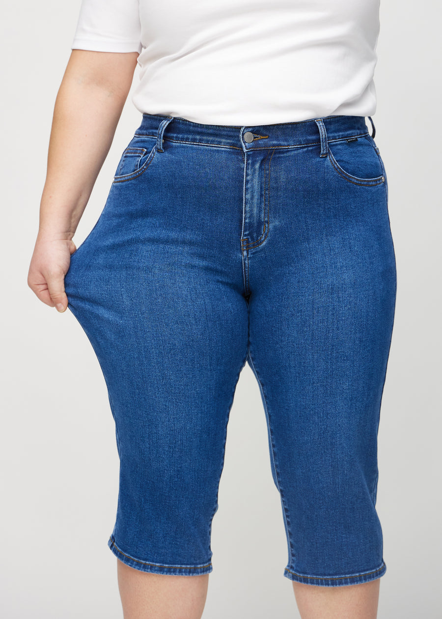 The plus-size model stretches the capris at the thigh to show the stretch.