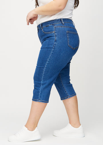Dark denim regular capris seen from the side on a plus-size model.