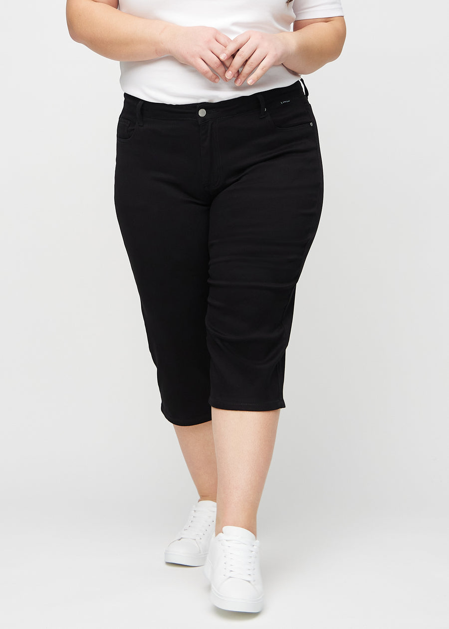 Black regular capris, model name Ravens, with a straight fit through the leg and ending just below the knee on a plus-size model, front view.
