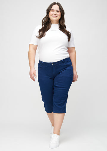 Full image of a plus-size model in dark blue regular capris.