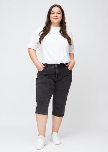 Full image of a plus-size model in dark grey denim regular capris.
