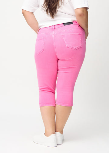 Skinny capris for women in pastel pink fabric, color Flamingos. Back view on a plus-size model, showing the fit and back pockets.