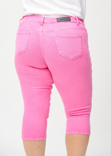 Skinny capris for women in pastel pink fabric, color Flamingos. Close-up from behind on a plus-size model, highlighting pockets and stitching.