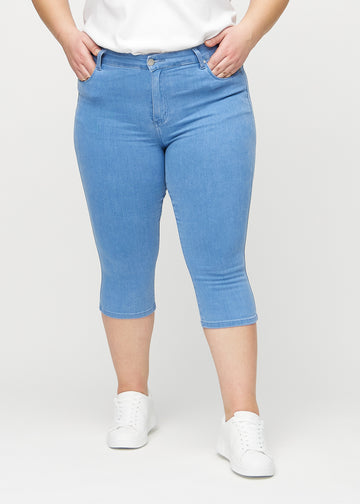 Skinny capris for women in blue fabric, color Geraniums. Front view on a plus-size model, showing the close-fitting legs ending just below the knee.