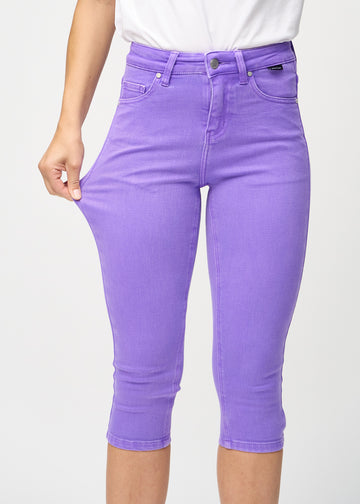 Skinny capris for women in pastel purple fabric, color Lavenders. A model stretches the fabric to demonstrate its flexibility.