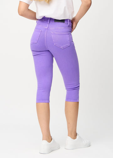 Skinny capris for women in pastel purple fabric, color Lavenders. Back view on a model, showing the fit and back pockets.