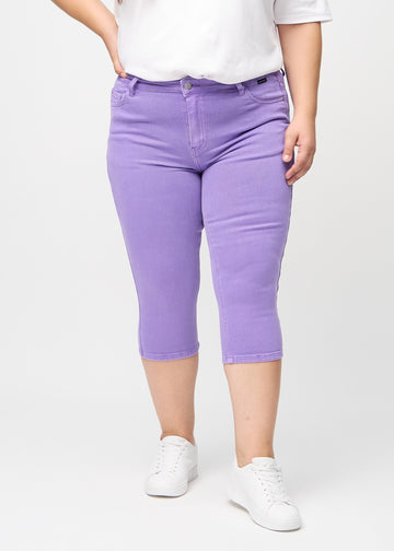 Skinny capris for women in pastel purple fabric, color Lavenders. Front view on a plus-size model, showing the close-fitting legs ending just below the knee.
