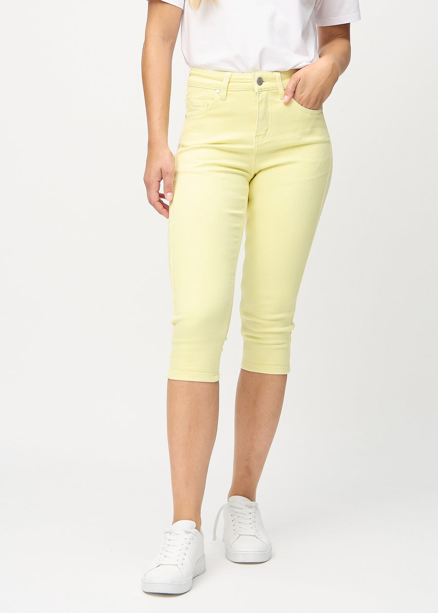 Skinny capris for women in pastel yellow fabric, color Lemonades. Front view on a model, showing the close-fitting legs ending just below the knee.