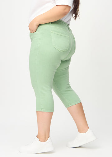 Skinny capris for women in pastel green fabric, color Mints. Side view on a plus-size model, showing the fitted cut.
