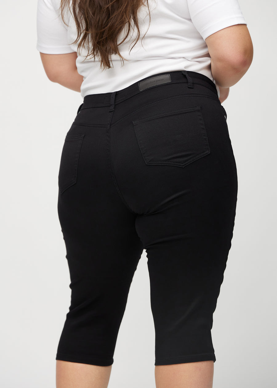 Black skinny capris seen from the back close up on a plus-size model to show details.
