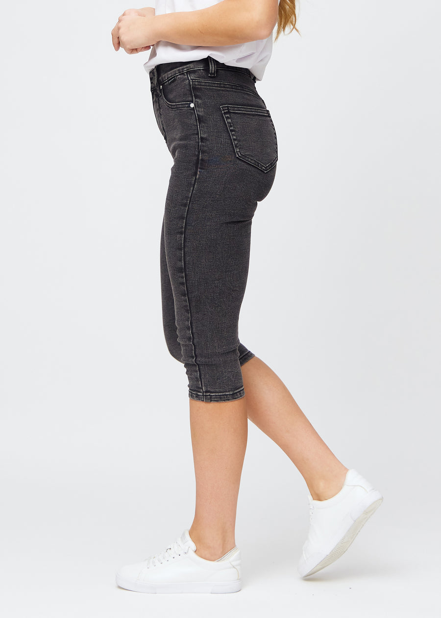 Woman wearing dark grey Shadows denim capris in a skinny fit, seen from the side.