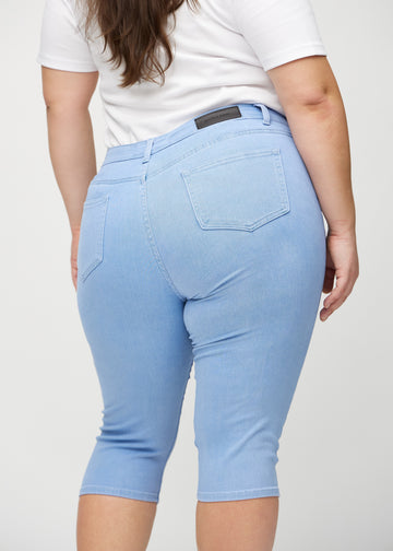 Skinny capris for women in light blue fabric, color Skies. Close-up from behind on a plus-size model, highlighting pockets and stitching.