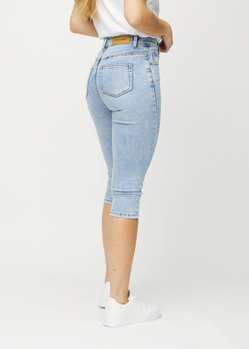 Skinny capris for women in light blue denim, color Waves. Back view on a model, showing the fit and back pockets.