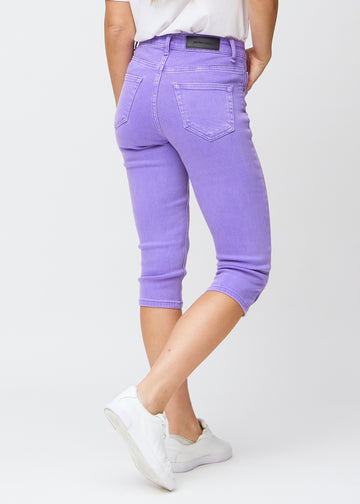 Slim capris for women in pastel purple jeans fabric, color Lavenders. Back view on a model, showing the fit, length and back pockets.
