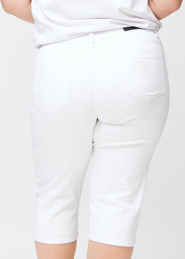 Slim capris for women in white jeans fabric, color Marguerites. Close-up from behind on a plus-size model, highlighting the back pockets and stitching.