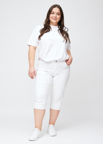 Slim capris for women in white jeans fabric, color Marguerites. Full-length view of a plus-size model wearing slim capris.