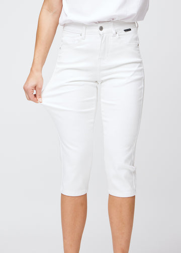 Slim capris for women in white jeans fabric, color Marguerites. A model pulls the fabric at the thigh to demonstrate stretch and flexibility.