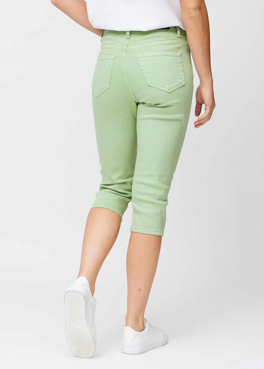 Slim capris for women in pastel light green jeans fabric, color Mints. Back view on a model, showing the fit, length and back pockets.