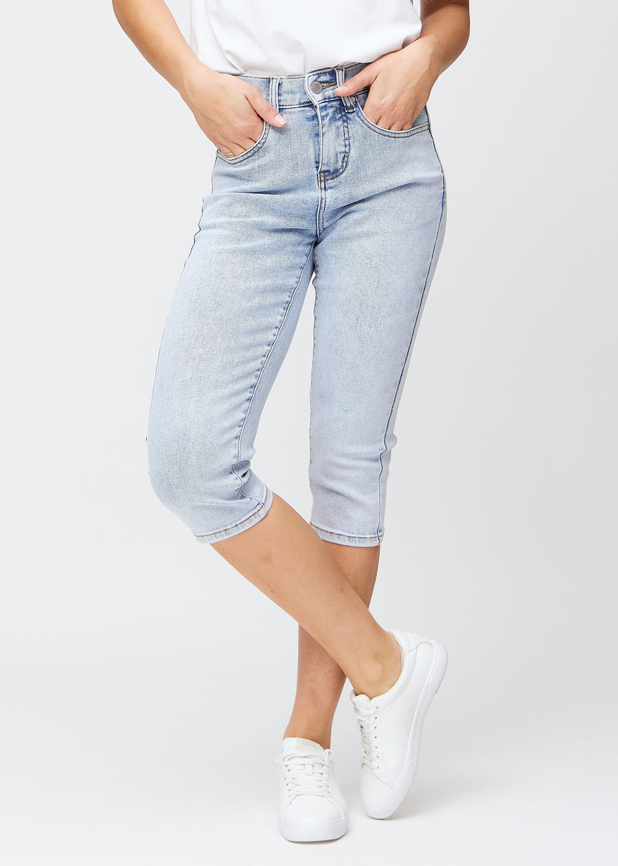 Light blue denim slim capris, colour Waves, with a tight fit that shapes the legs and ends just below the knee, seen from the front.