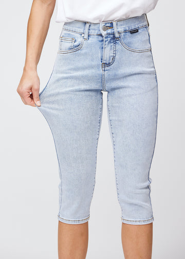 The model stretches the capris at the thigh to show the soft and flexible stretch in the light blue denim.