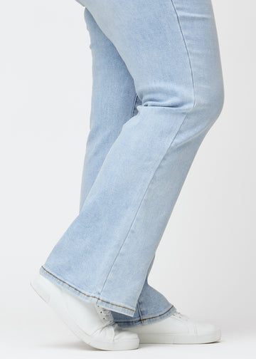 Light blue mid-rise bootcut jeans in Waves. Close-up of the ankle area on a plus-size model, showing the subtle bootcut flare.