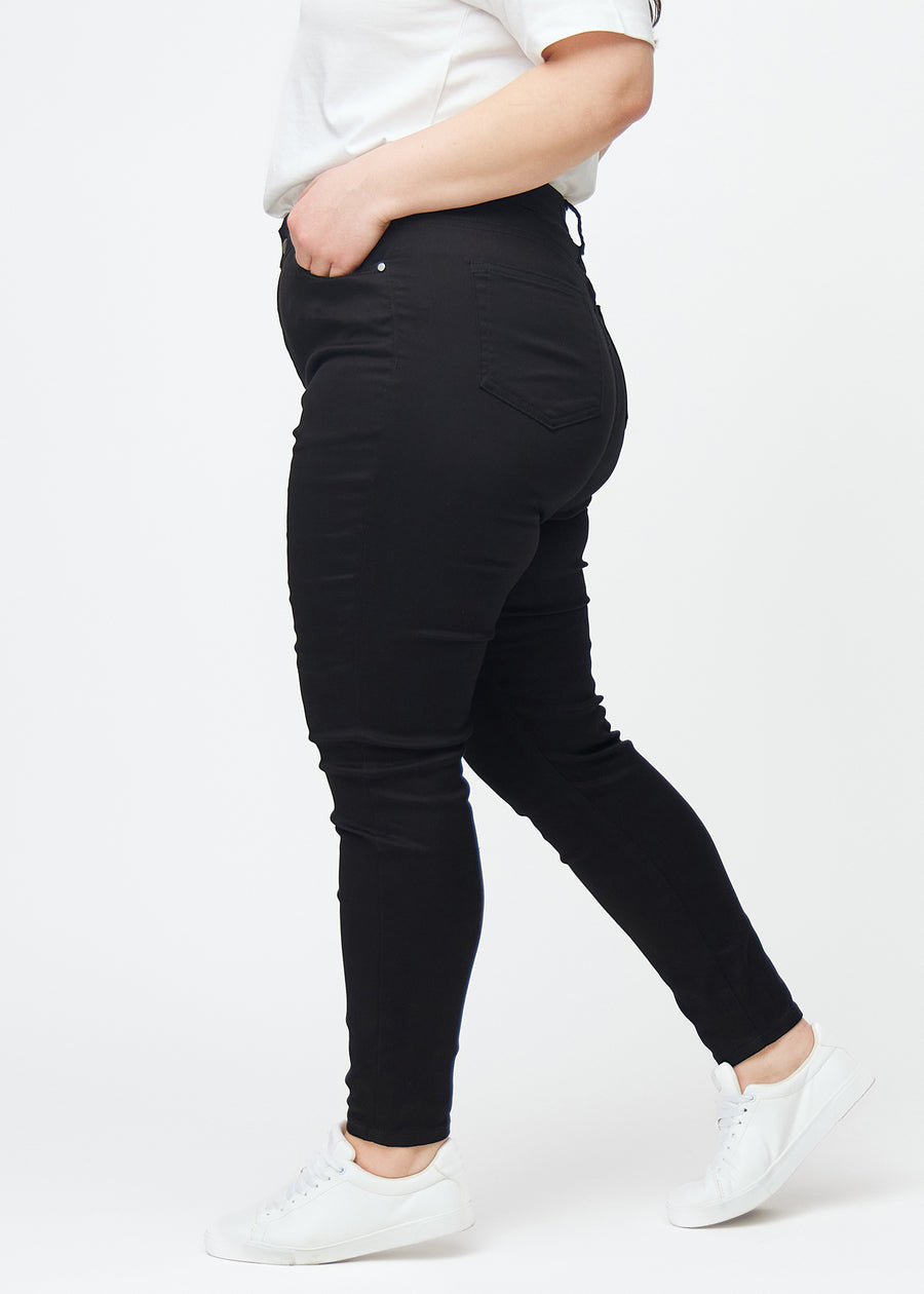Black plus size high rise skinny jeans for women in the color Ravens are seen from the side on a model.