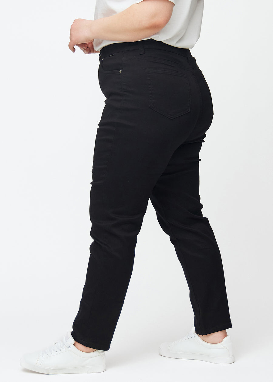 Black high-waisted slim jeans seen from the side on a plus-size model.
