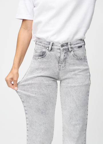 Loose jeans for women in light grey, color Ashes. A model stretches the denim at the thigh to show the fabric&