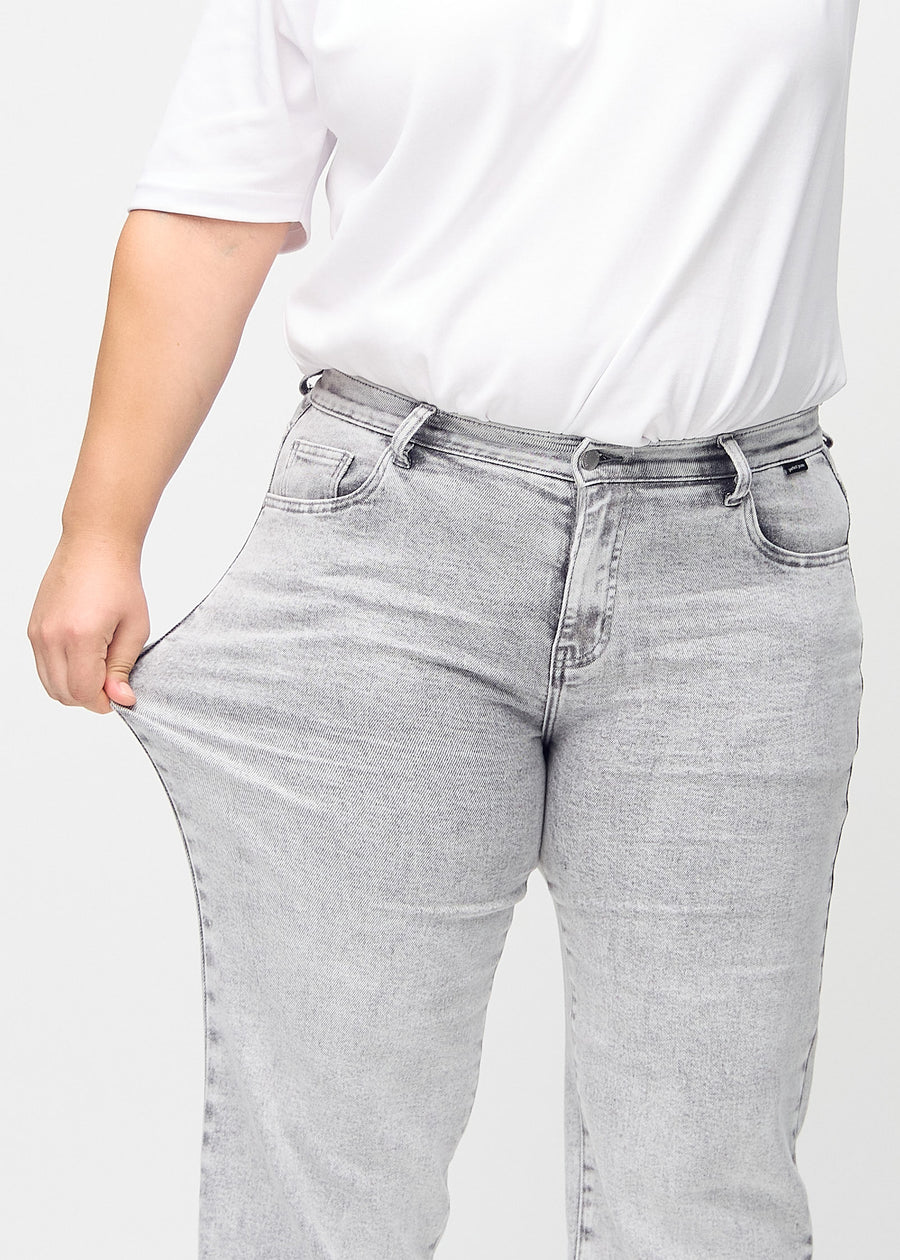 Loose jeans for women in light grey, color Ashes. A plus-size model stretches the denim at the thigh to show the fabric&
