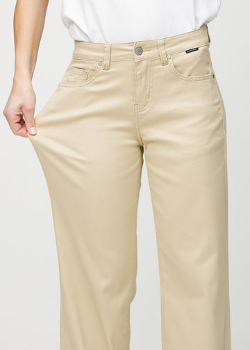 Loose jeans for women in beige, color Gazelles. A model stretches the denim at the thigh to show the fabric&